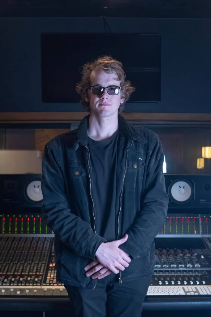 Rhyon Cook standing in front of a mixing console in Melbourne, music producer from Warrnambool.